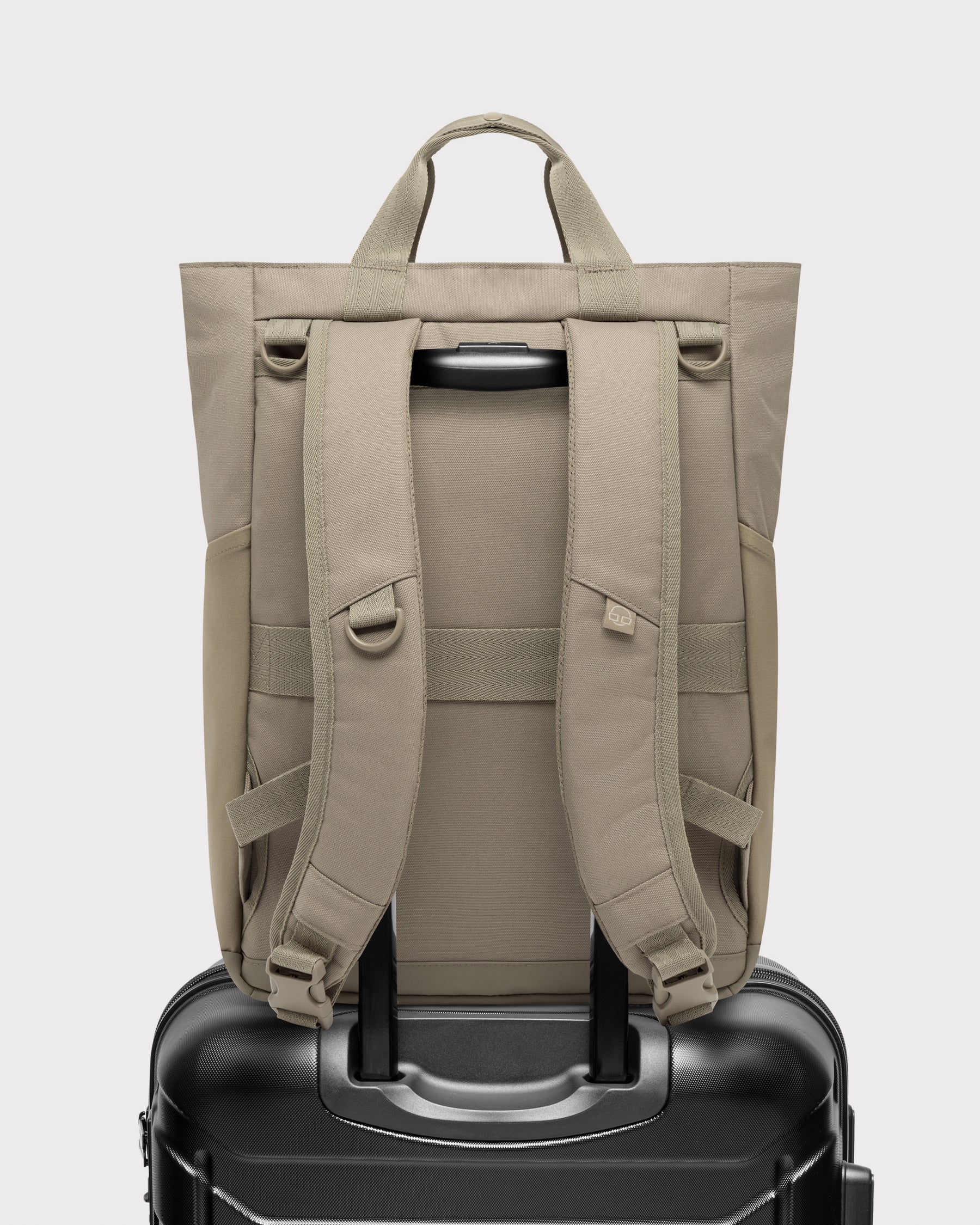 Rückansicht der Wickeltasche 'Blair' in Beige auf einem schwarzen Trolley-Koffer befestigt