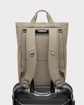 Rückansicht der Wickeltasche 'Blair' in Beige auf einem schwarzen Trolley-Koffer befestigt