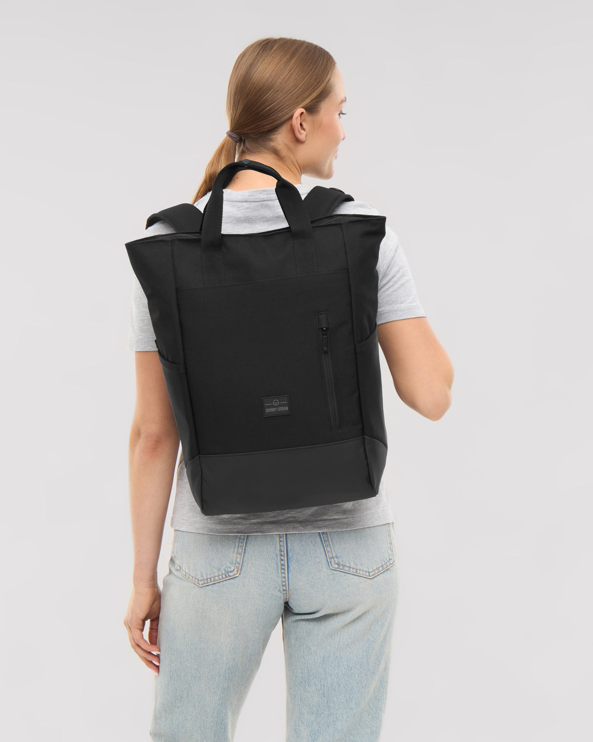 Frau von hinten mit schwarzer Wickeltasche 'Blair' von Johnny Urban, graues T-Shirt, helle Jeans