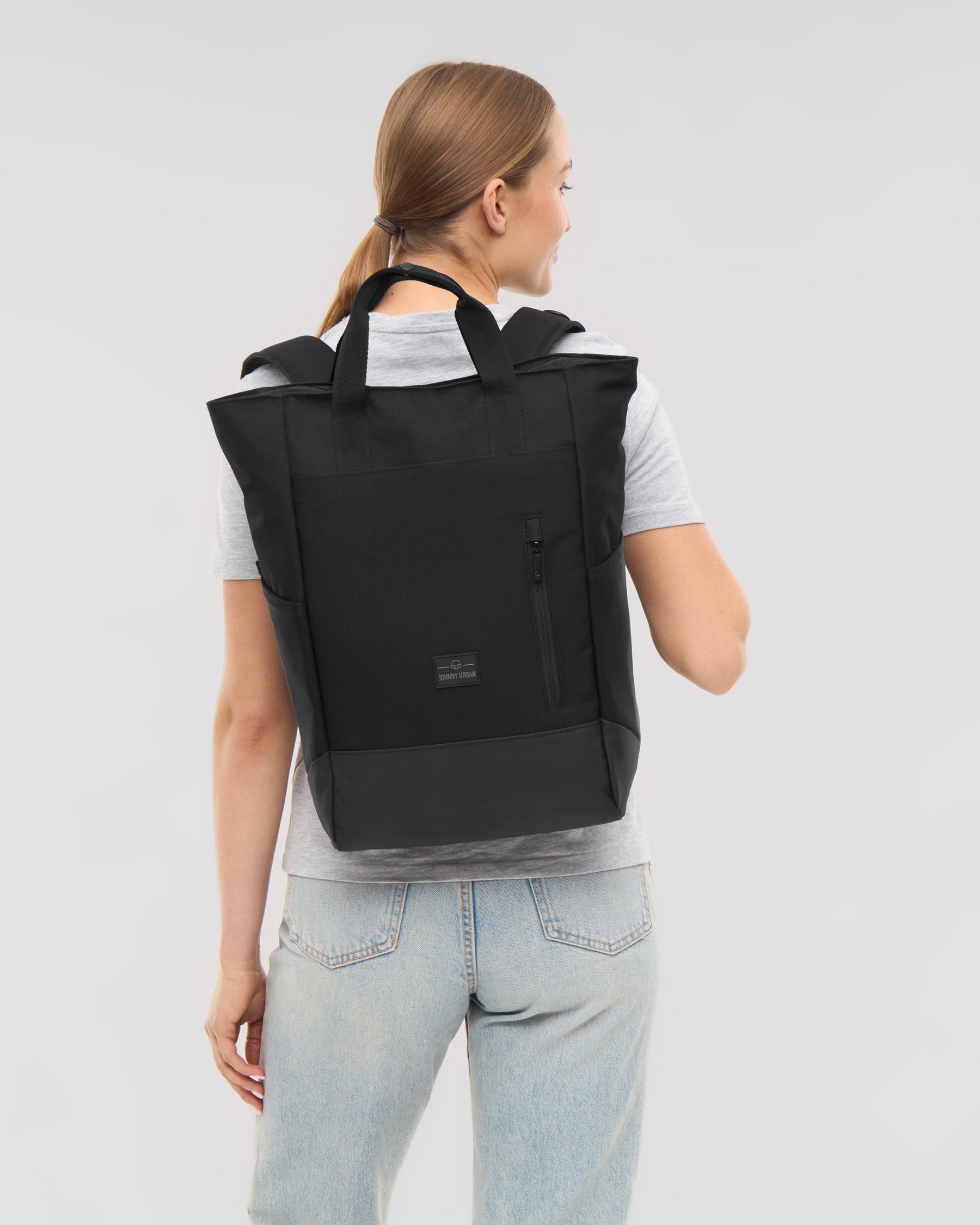 Frau von hinten mit schwarzer Wickeltasche 'Blair' von Johnny Urban, graues T-Shirt, helle Jeans