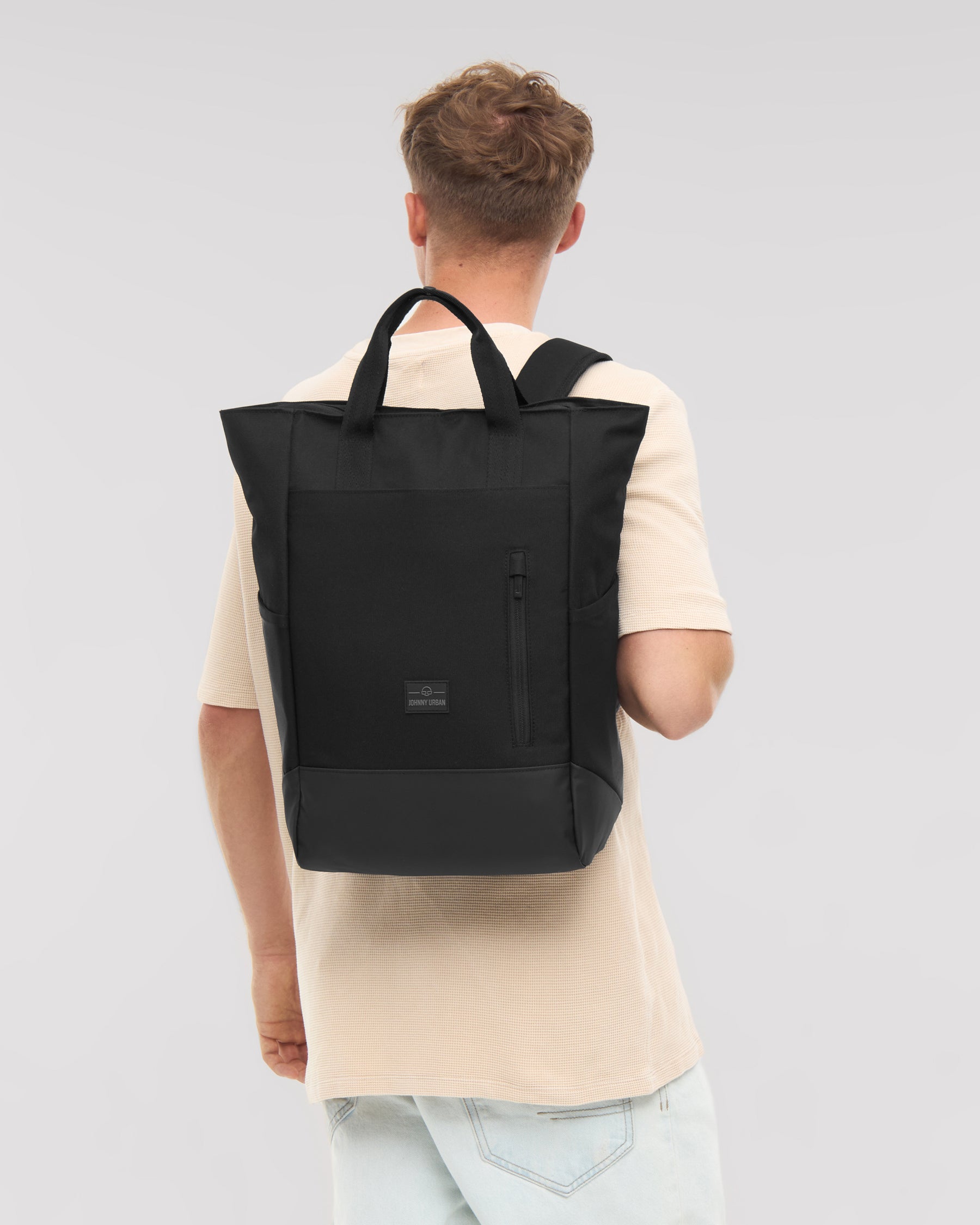 Mann von hinten mit schwarzer Wickeltasche 'Blair' als Rucksack