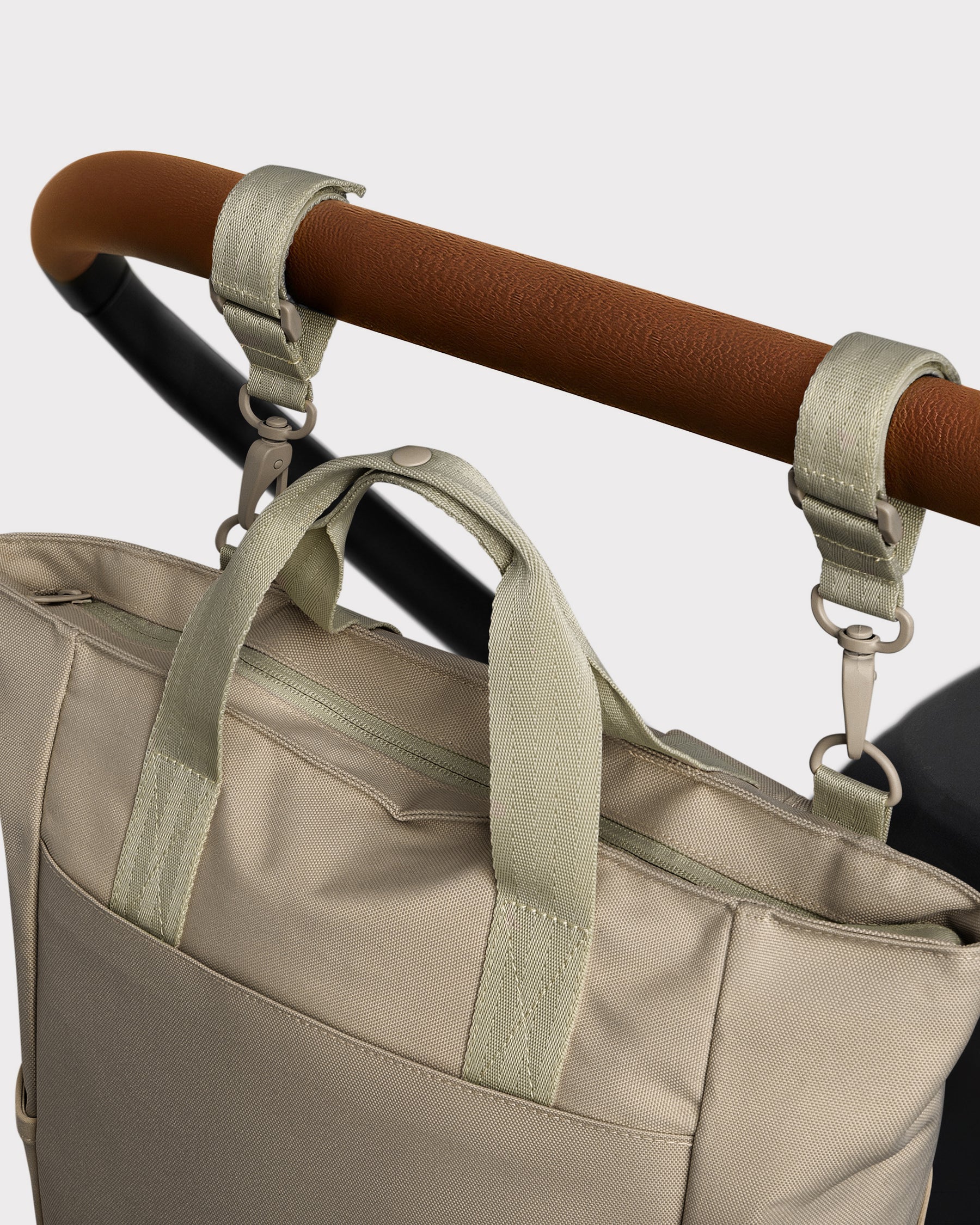 Beige Wickeltasche 'Blair' aus robustem Material, befestigt an Kinderwagen mit zwei Schlaufen