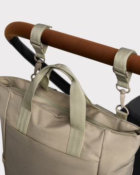 Beige Wickeltasche 'Blair' aus robustem Material, befestigt an Kinderwagen mit zwei Schlaufen