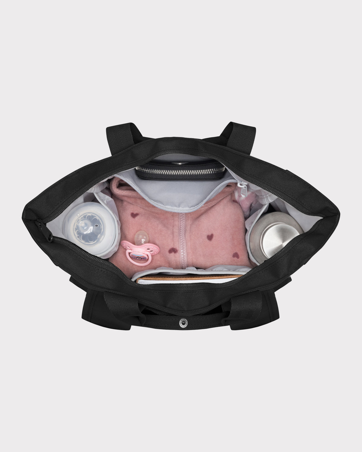 Schwarze Wickeltasche 'Blair' von oben mit rosa Babyjacke, Schnuller, Fläschchen und Thermoskanne im Inneren