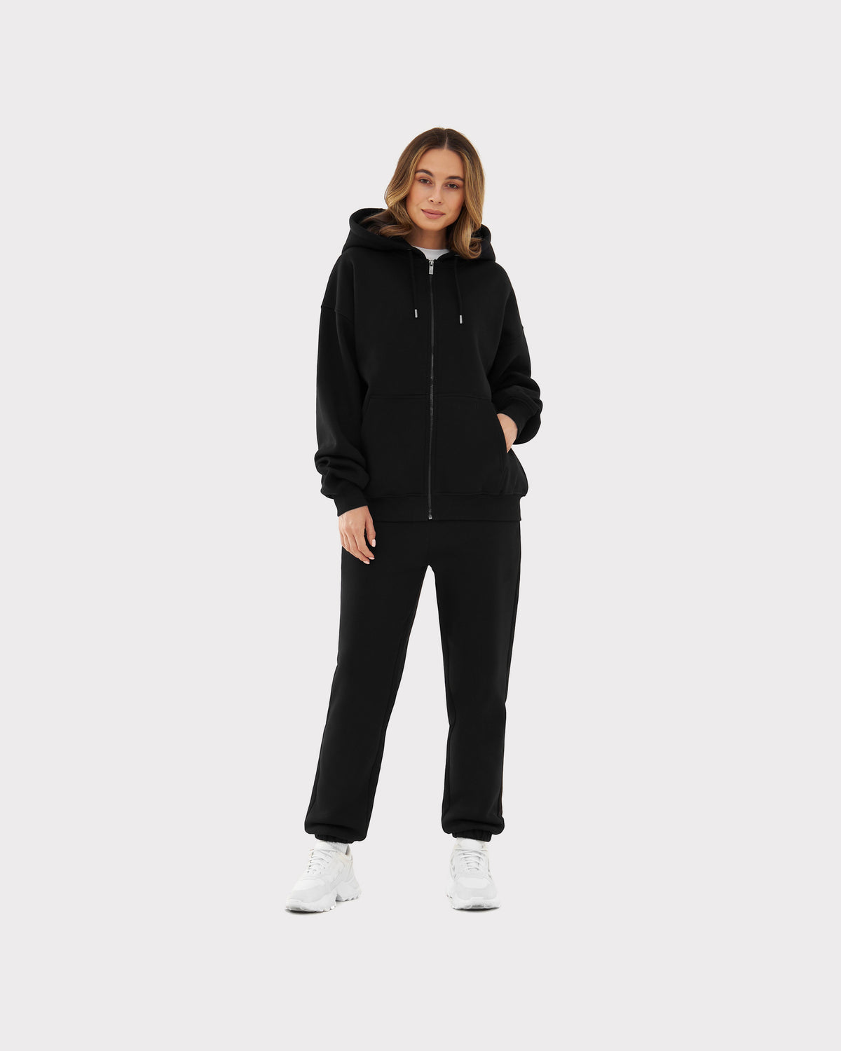 Frau trägt schwarzen oversized Zip-Hoodie 'Caleb' mit Kapuze und schwarzen Jogginghosen