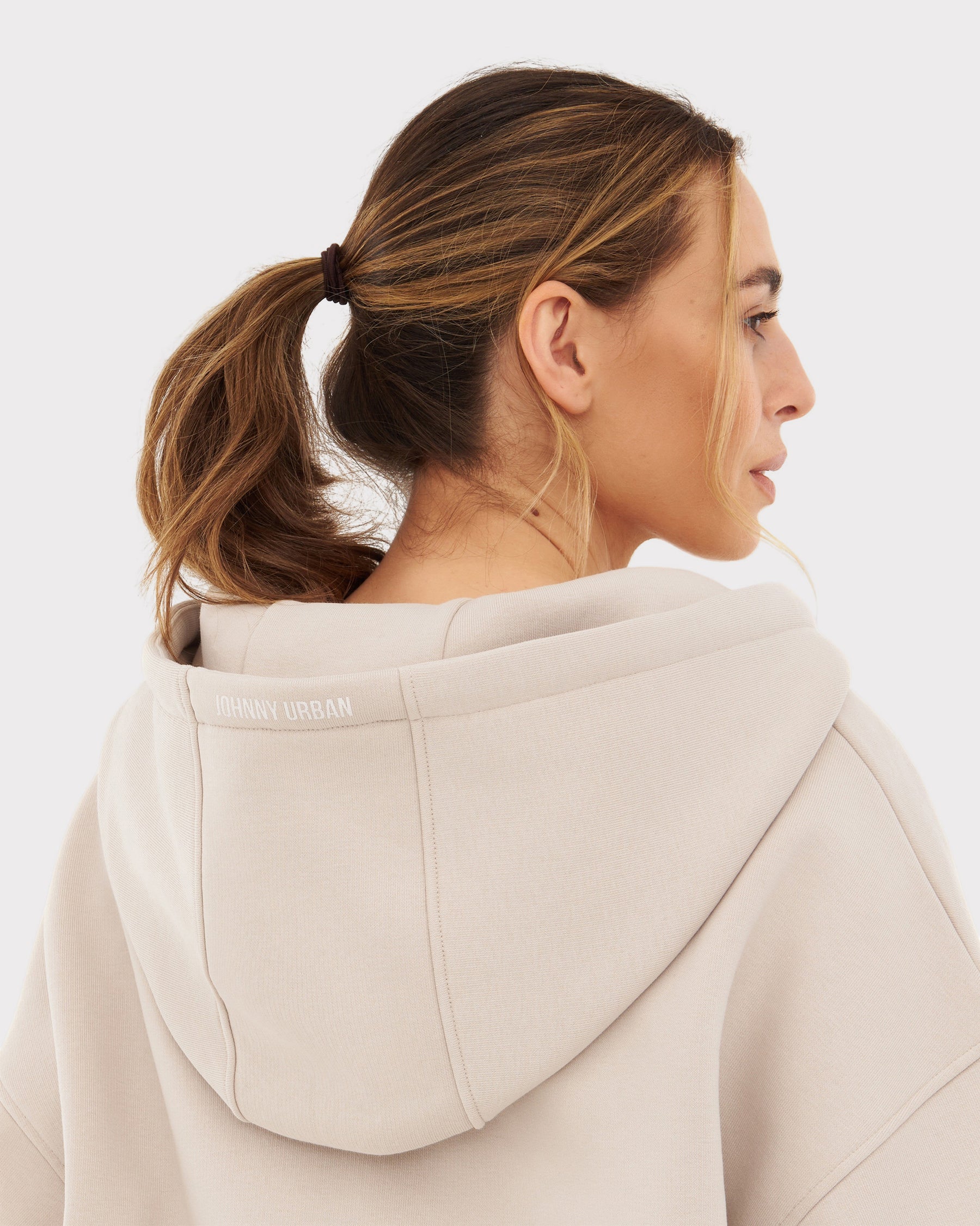 Rückansicht einer Frau mit beiger oversized Kapuzenjacke 'Caleb' von Johnny Urban, Pferdeschwanz