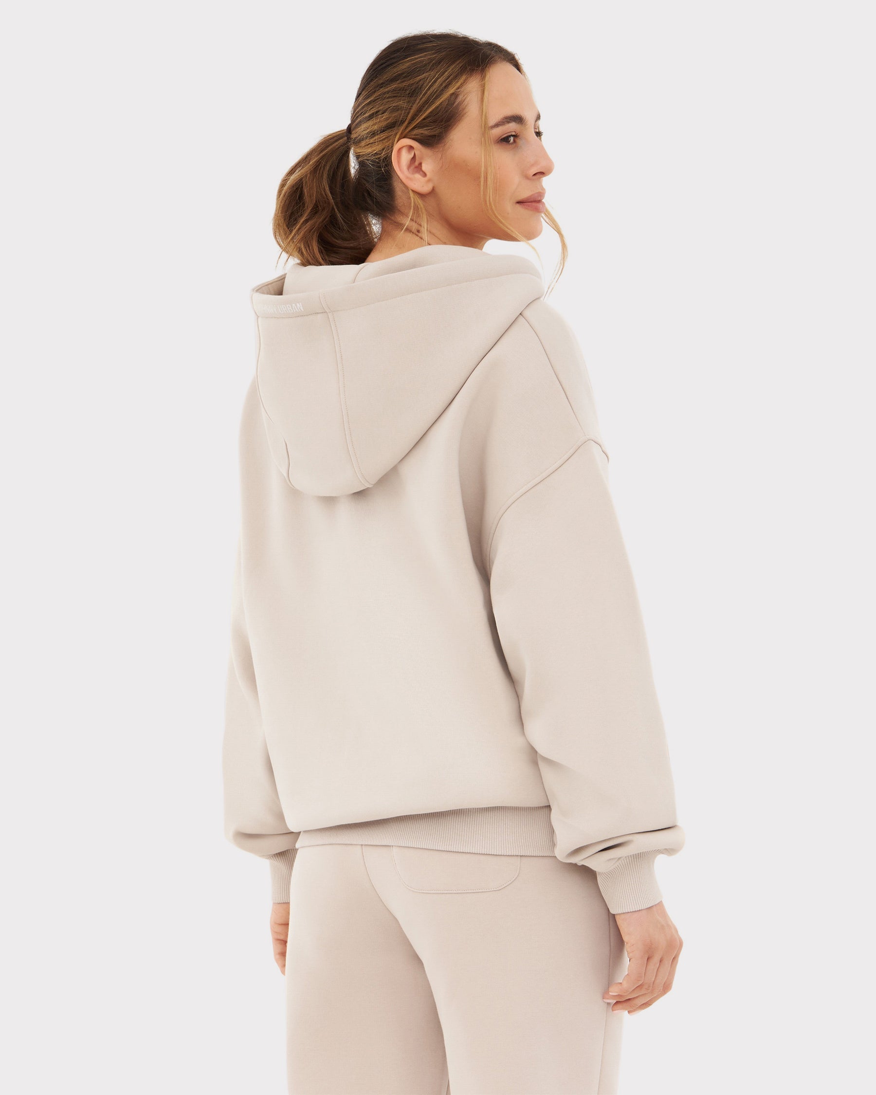 Frau trägt beigen Johnny Urban Oversized Zip Hoodie 'Caleb' von hinten mit Kapuze und Bündchen an Ärmeln und Saum