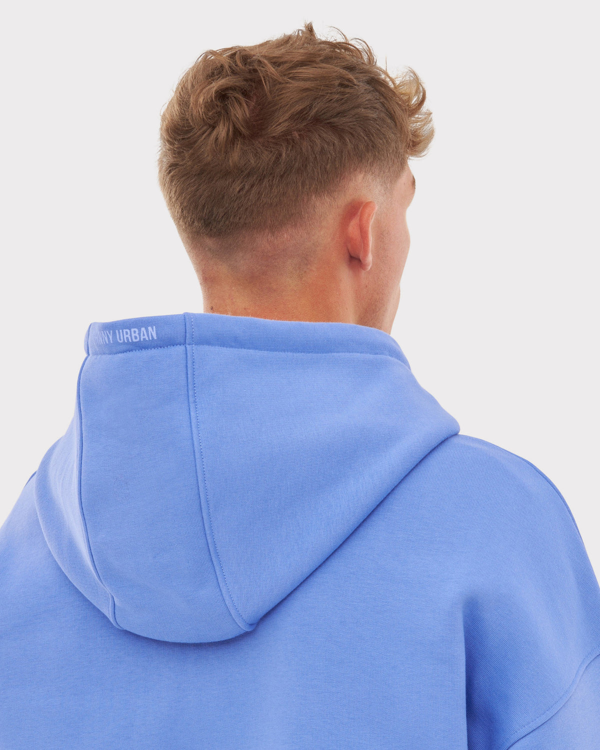 Rückansicht eines Mannes mit kurzem Haar, der eine blaue, oversized Zip-Hoodie 'Caleb' von Johnny Urban trägt
