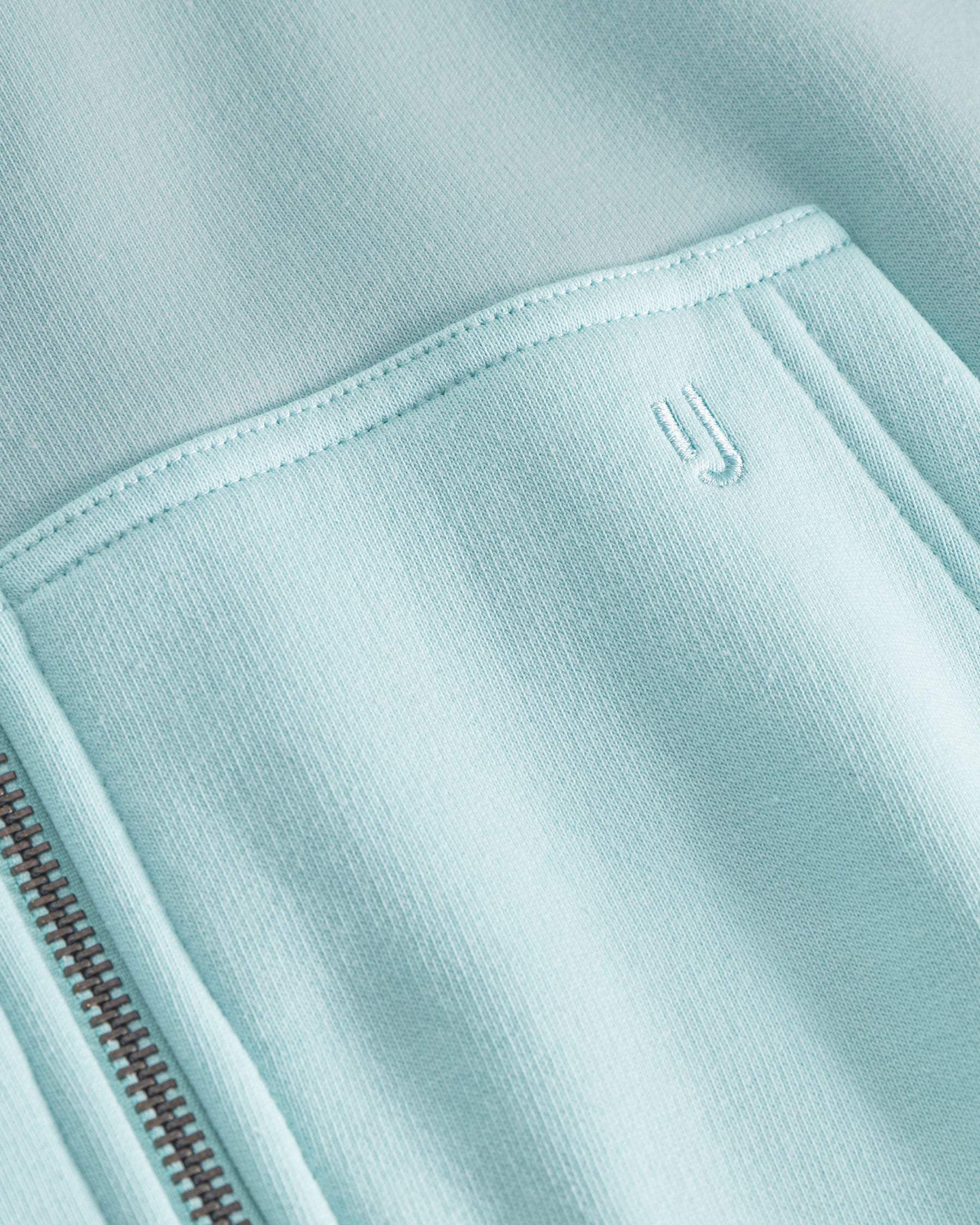 Nahaufnahme der Tasche und des feinen Reißverschlusses des oversized Zip-Hoodies 'Caleb' in eisblau