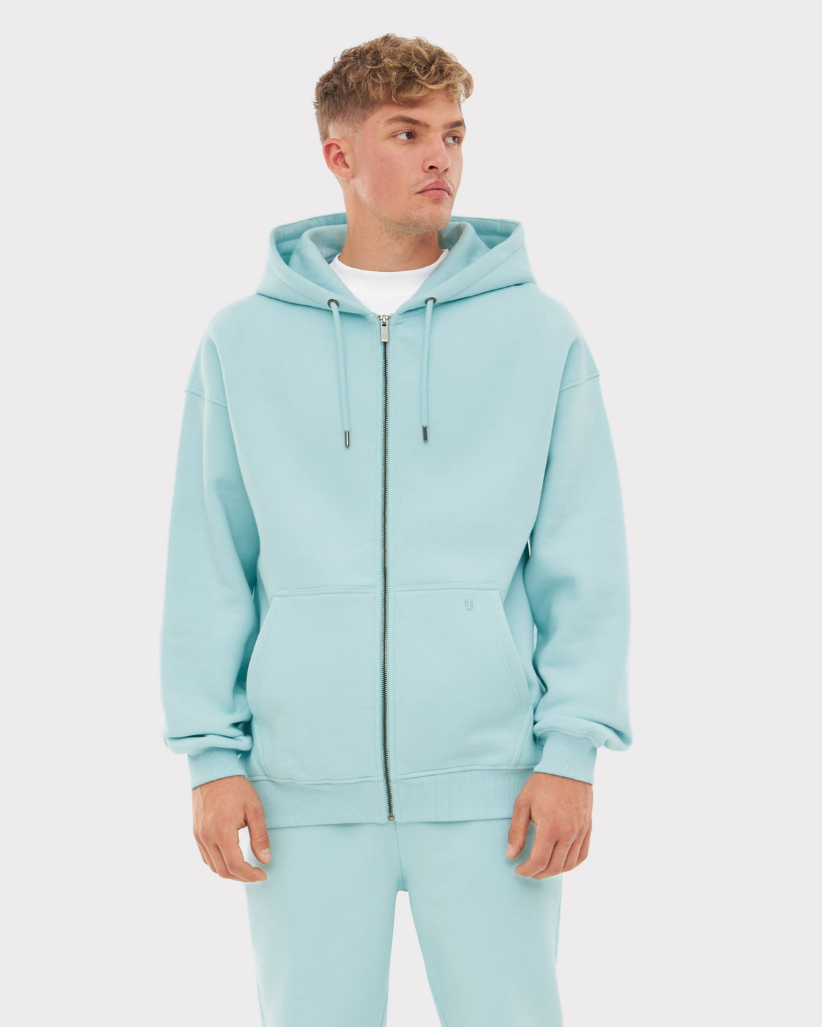 Mann trägt hellblauen oversized Zip-Hoodie 'Caleb' mit Kapuze und Kängurutaschen
