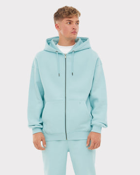 Mann trägt hellblauen oversized Zip-Hoodie 'Caleb' mit Kapuze und Kängurutaschen