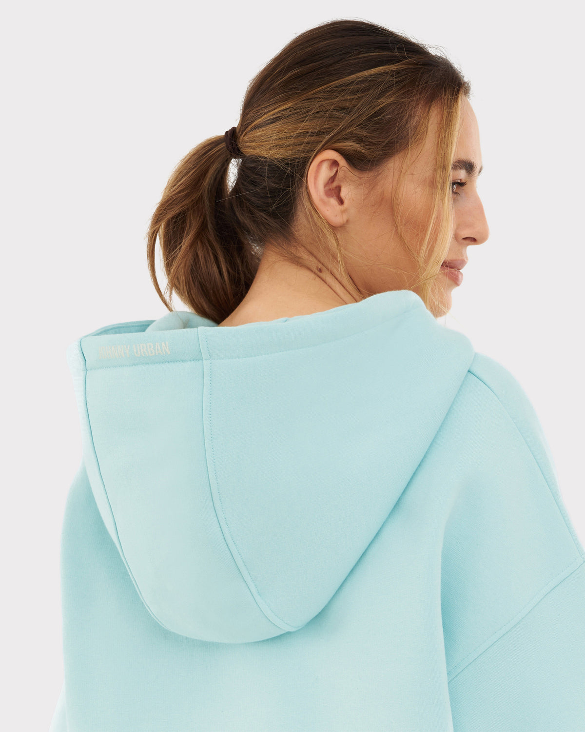 Rückansicht einer Frau mit Zopf, die eine eisblau oversized Zip Hoodie 'Caleb' von Johnny Urban trägt