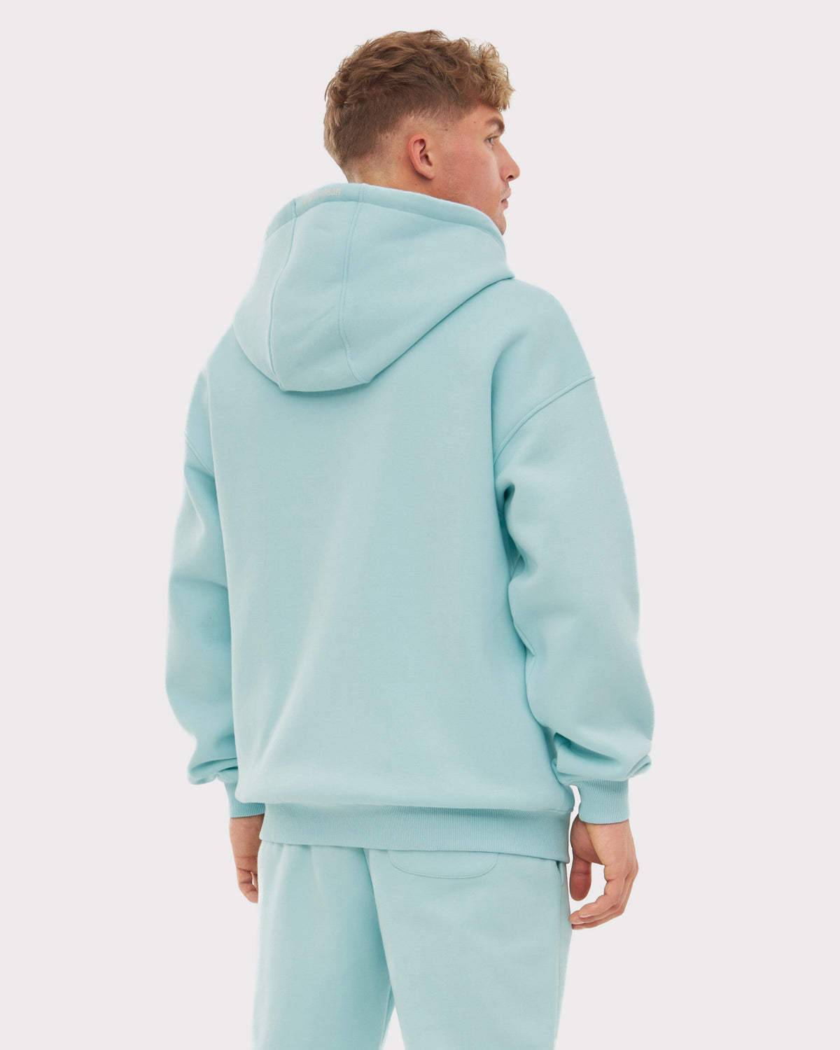 Mann trägt oversized Zip-Hoodie 'Caleb' in eisblau von hinten