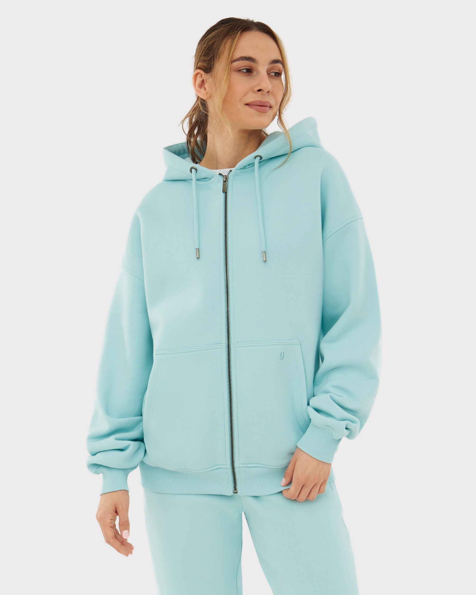 Frau trägt oversized Zip-Hoodie 'Caleb' in modernem Eisblau mit Kapuze und Kängurutasche