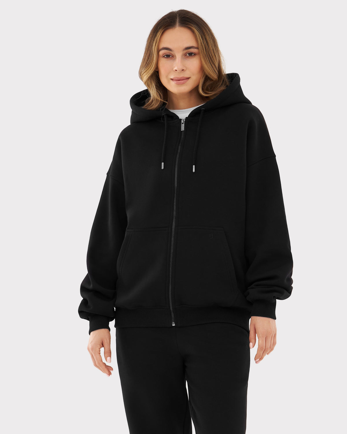 Frau trägt oversized Zip-Hoodie 'Caleb' in Schwarz mit Kapuze und Kängurutasche