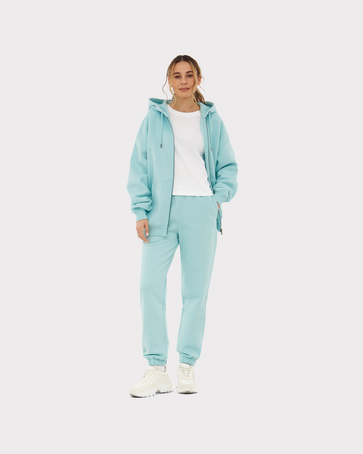 Frau trägt oversized Zip-Hoodie 'Caleb' in Eisblau mit passender Jogginghose und weißem T-Shirt