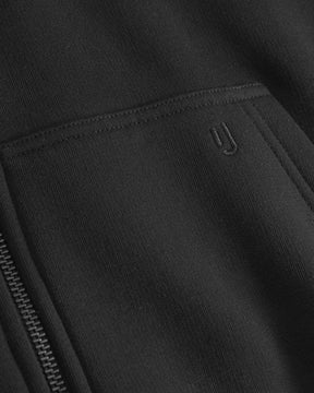 Detailansicht der schwarzen Jumbo-Zip-Hoodie "Caleb" mit Reißverschluss und gesticktem 'yj'-Logo auf der Tasche
