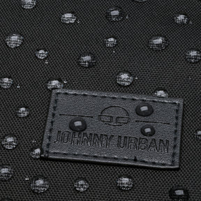 Nahaufnahme von wasserabweisendem schwarzem Textil mit Johnny Urban Lederlabel und Wassertropfen darauf