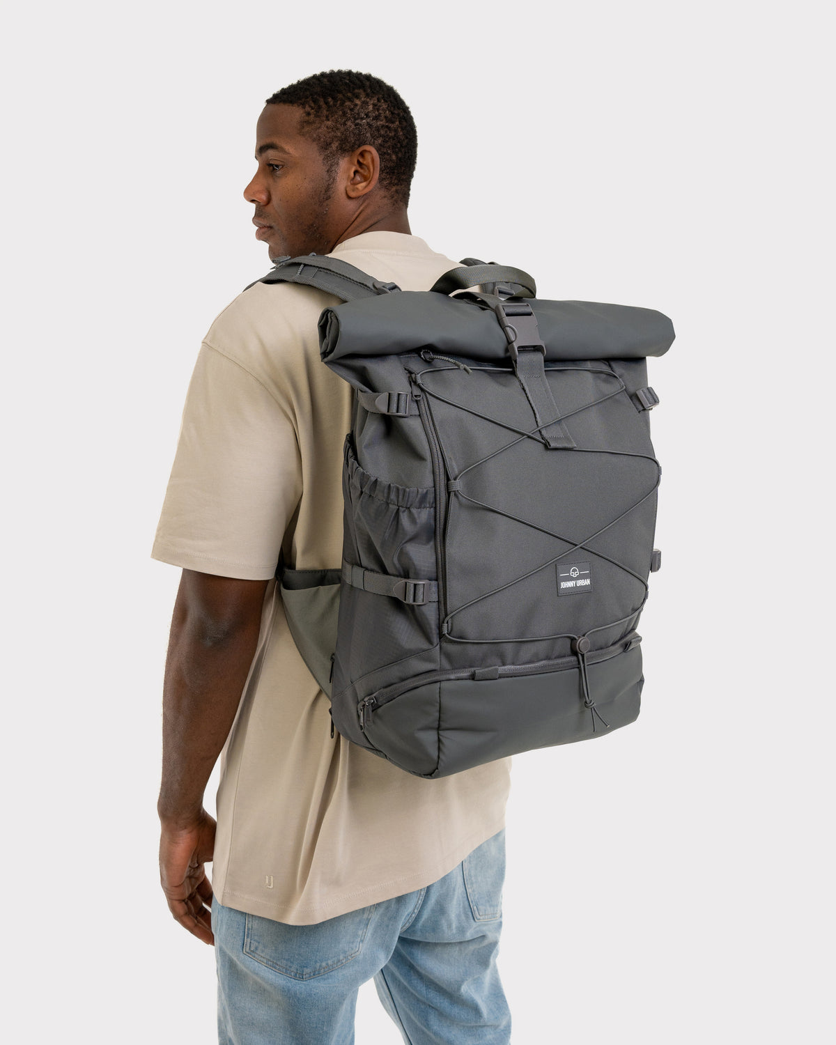 Mann trägt beigen T-Shirt und Jeans mit schwarzem Johnny Urban Reiserucksack 'Allen Large Travel'