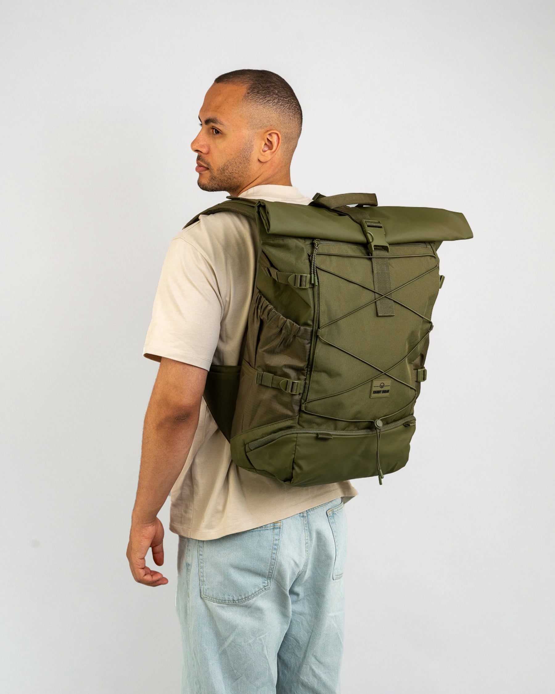 Mann trägt olivgrünen Johnny Urban Reiserucksack 'Allen Large Travel' mit gerolltem Verschluss und elastischem Frontband
