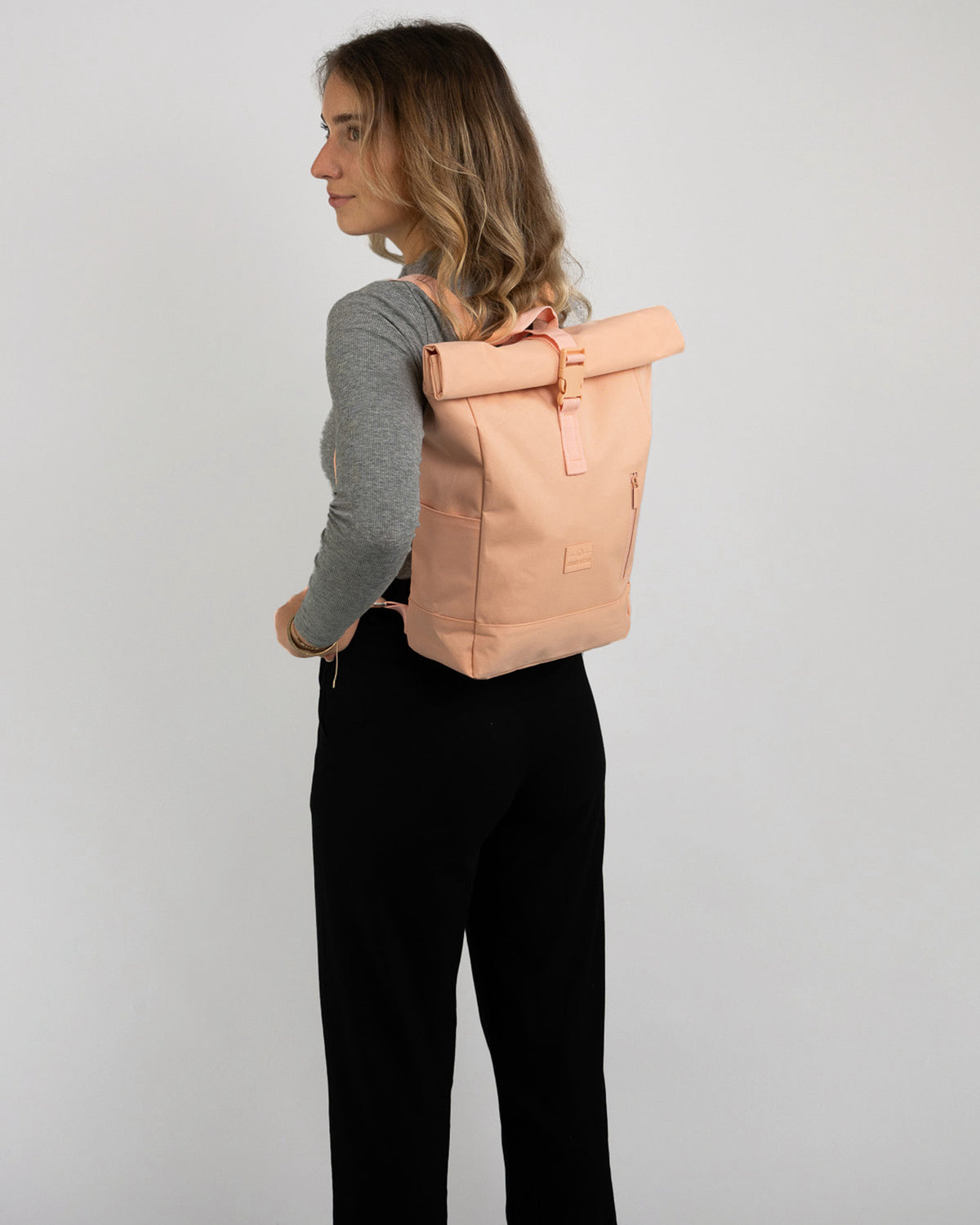 Frau trägt Johnny Urban Rolltop Rucksack 'Robin Small' in Pfirsichfarbe