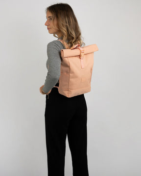 Frau trägt Johnny Urban Rolltop Rucksack 'Robin Small' in Pfirsichfarbe