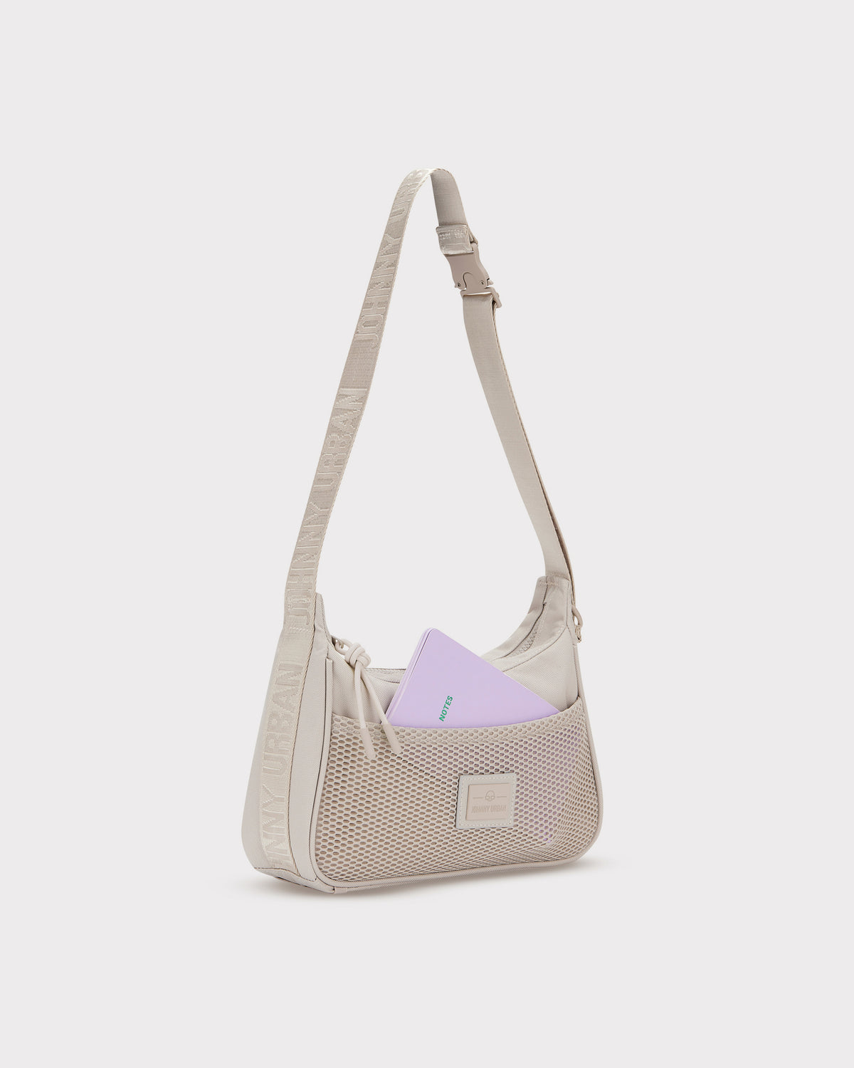 Beige Handtasche 'Maddy' mit Netzvortasche und verstellbarem Schulterriemen, lila Notizbuch steckt in der Tasche