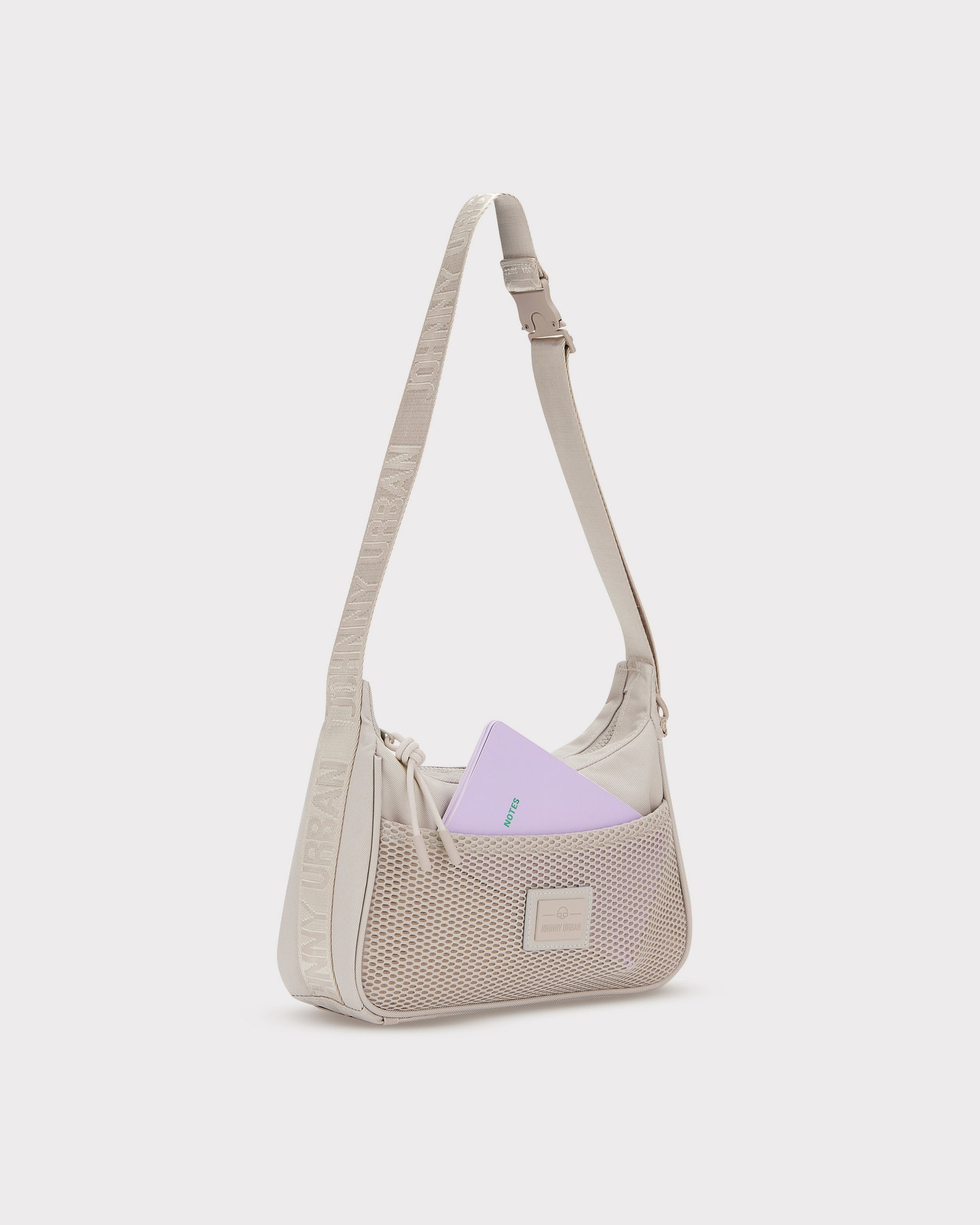 Beige Handtasche 'Maddy' mit Netzvortasche und verstellbarem Schulterriemen, lila Notizbuch steckt in der Tasche
