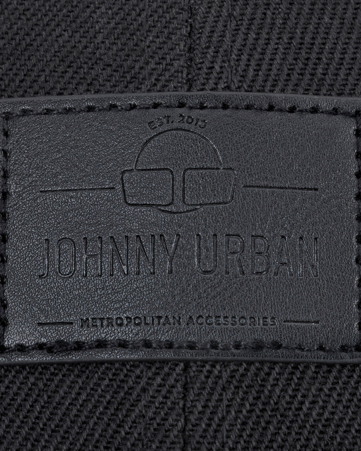 Schwarzes gewebtes Material mit Johnny Urban Lederetikett und eingraviertem Text 'Est. 2015', 'Johnny Urban', 'Metropolitan Accessories'