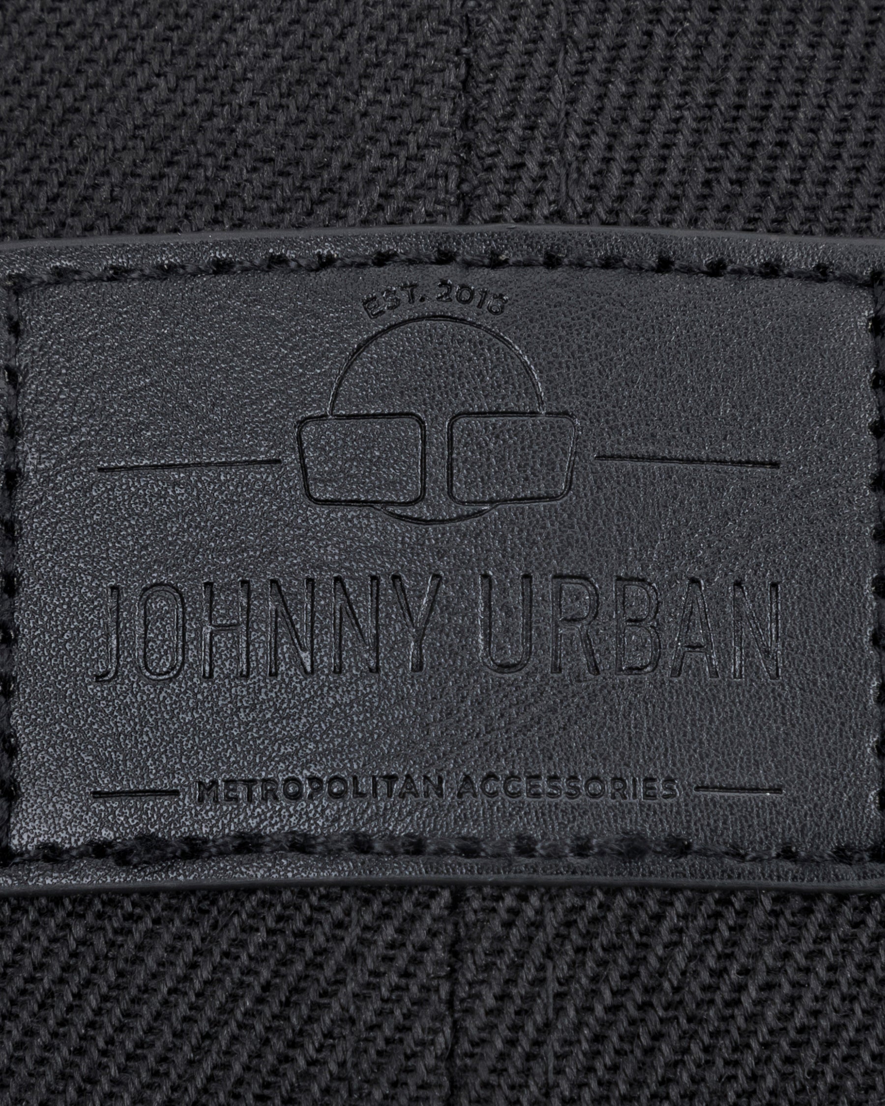 Schwarzes gewebtes Material mit Johnny Urban Lederetikett und eingraviertem Text 'Est. 2015', 'Johnny Urban', 'Metropolitan Accessories'