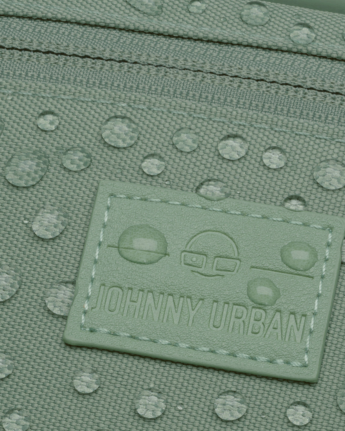 Nahaufnahme der wasserabweisenden grünen Bauchtasche 'Ben' von Johnny Urban mit Tropfen auf der Oberfläche