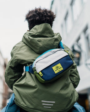 Kind trägt grüne Jacke und bunte Kinder Bauchtasche 'Felix' von Johnny Urban auf dem Rücken