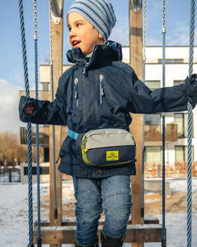 Kind trägt Kinder Bauchtasche 'Felix' in Blau, Weiß und Grün beim Balancieren auf einem Seil im Schnee