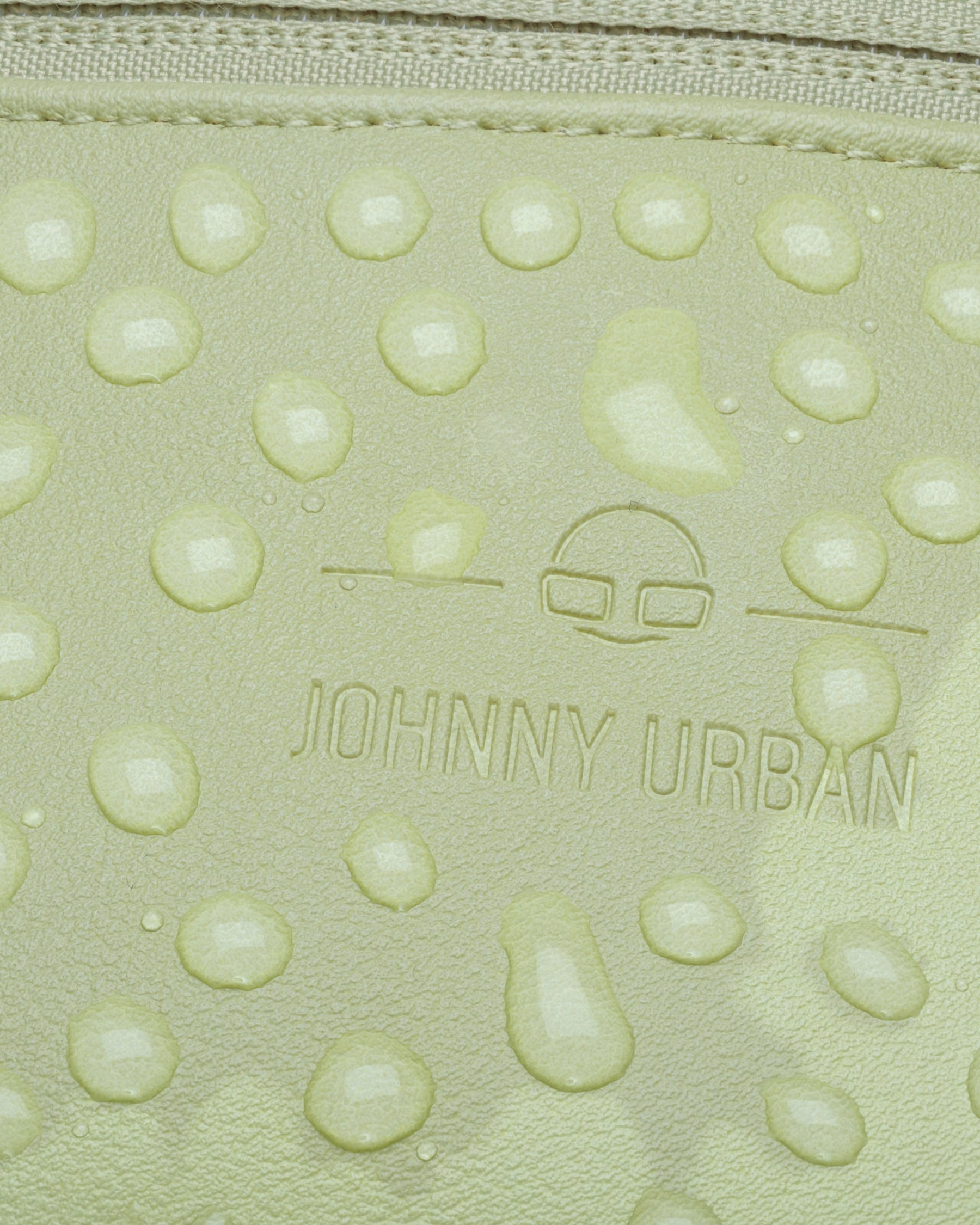 Nahaufnahme wasserabweisender Kunstlederoberfläche der limefarbenen Bauchtasche 'Toni' mit Johnny Urban Logo