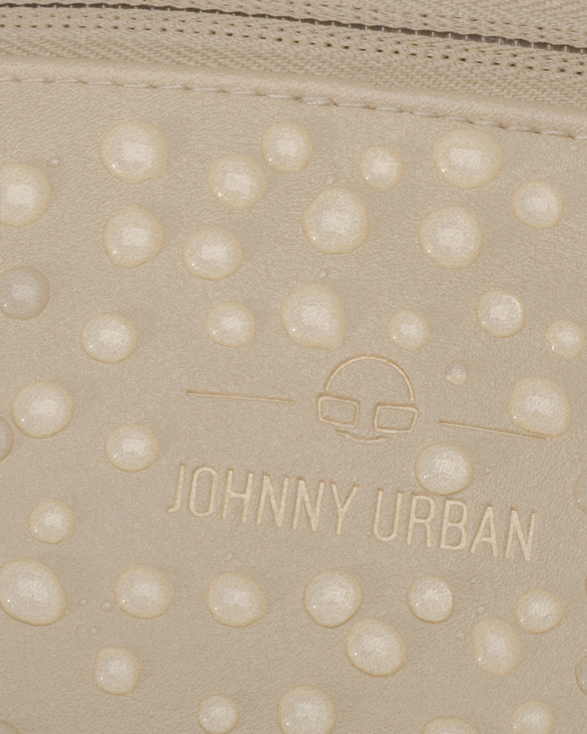 Nahaufnahme der wasserabweisenden, beigefarbenen Kunstleder-Oberfläche der Bauchtasche 'Toni' mit Johnny Urban Logo