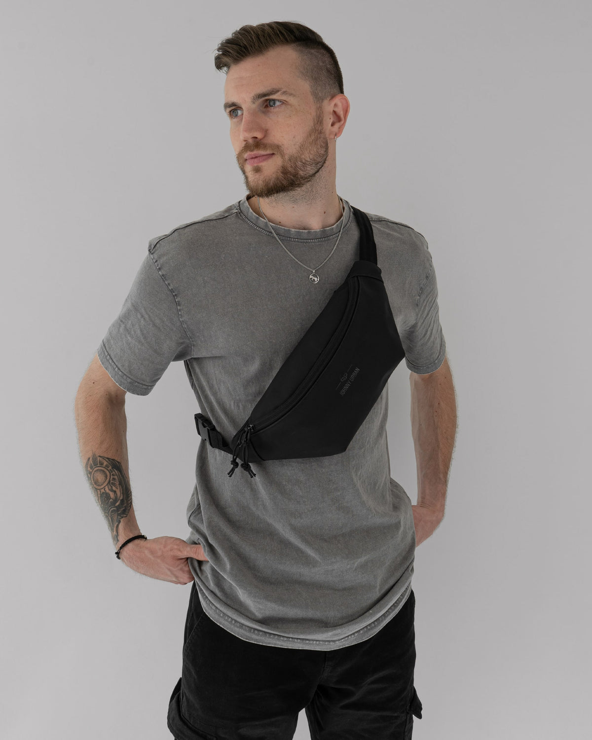 Mann mit grauem T-Shirt trägt die schwarze Bauchtasche 'Riley' von Johnny Urban diagonal über der Brust