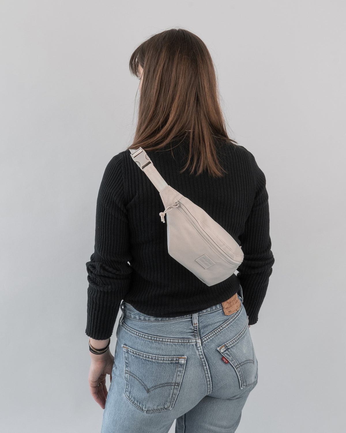 Frau von hinten mit schwarzem Pullover, blauer Jeans und beiger Bauchtasche 'Erik Small' von Johnny Urban
