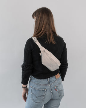Frau von hinten mit schwarzem Pullover, blauer Jeans und beiger Bauchtasche 'Erik Small' von Johnny Urban