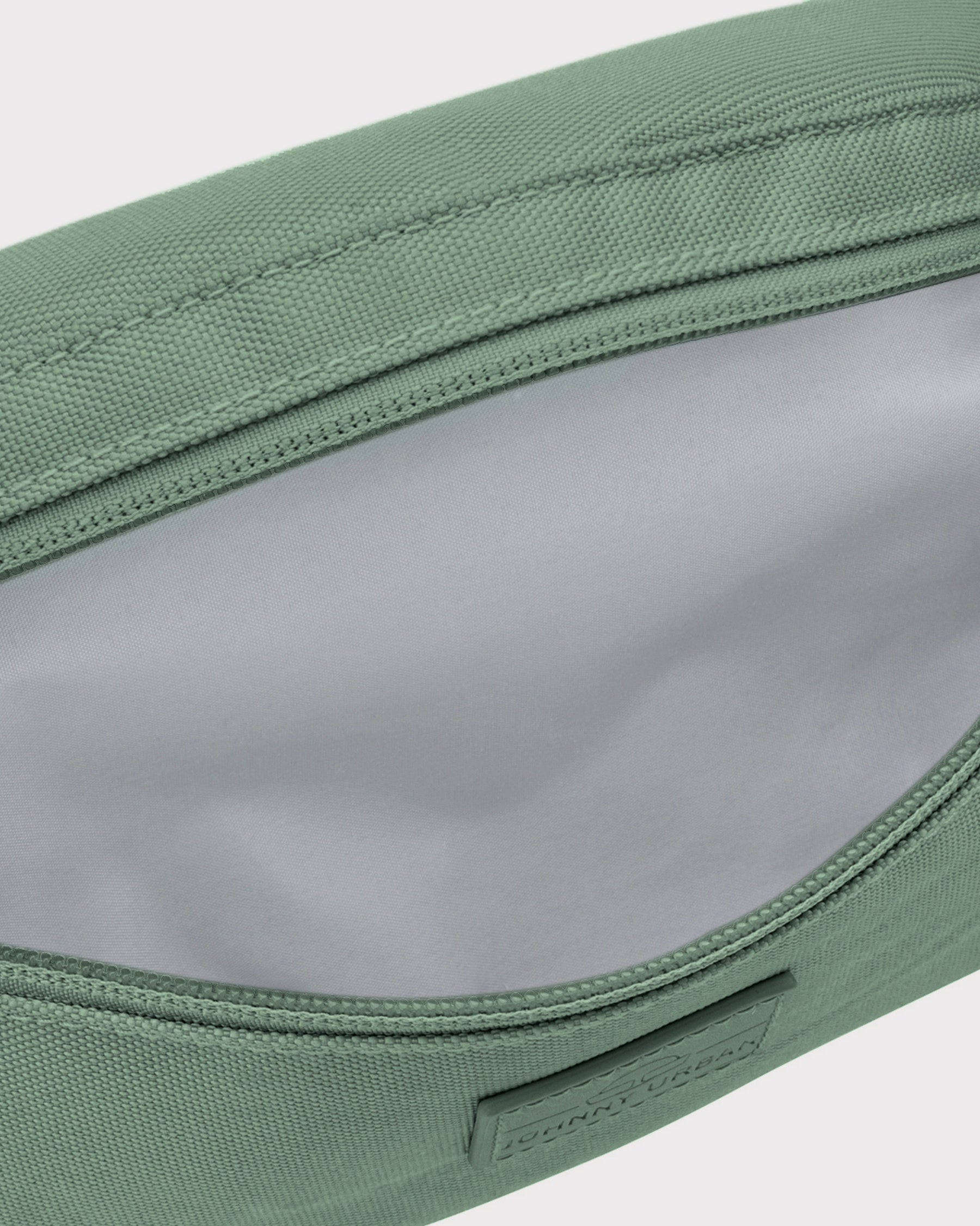 Grüne nachhaltige Bauchtasche 'Erik Small' mit geöffneter Haupttasche und grauem Innenfutter