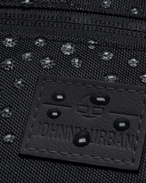 Nahaufnahme der wasserabweisenden schwarzen Bauchtasche 'Ben' mit geprägtem Johnny Urban Logo und Wassertropfen