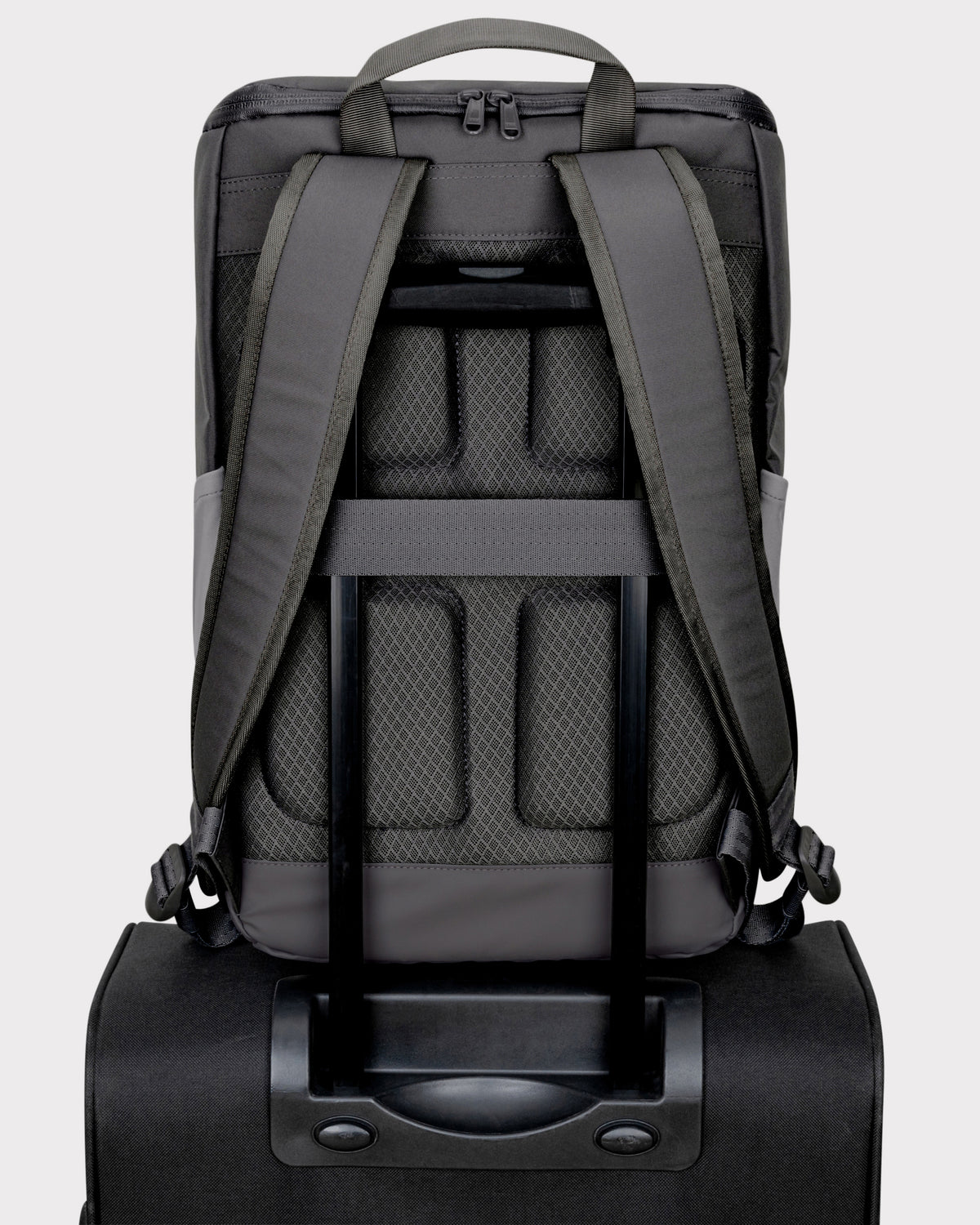 Rückansicht des grauen Business-Rucksacks Jasper mit gepolsterten Trägern, gepolstertem Rücken und Befestigungsschlaufe über dem Griff eines Trolleys