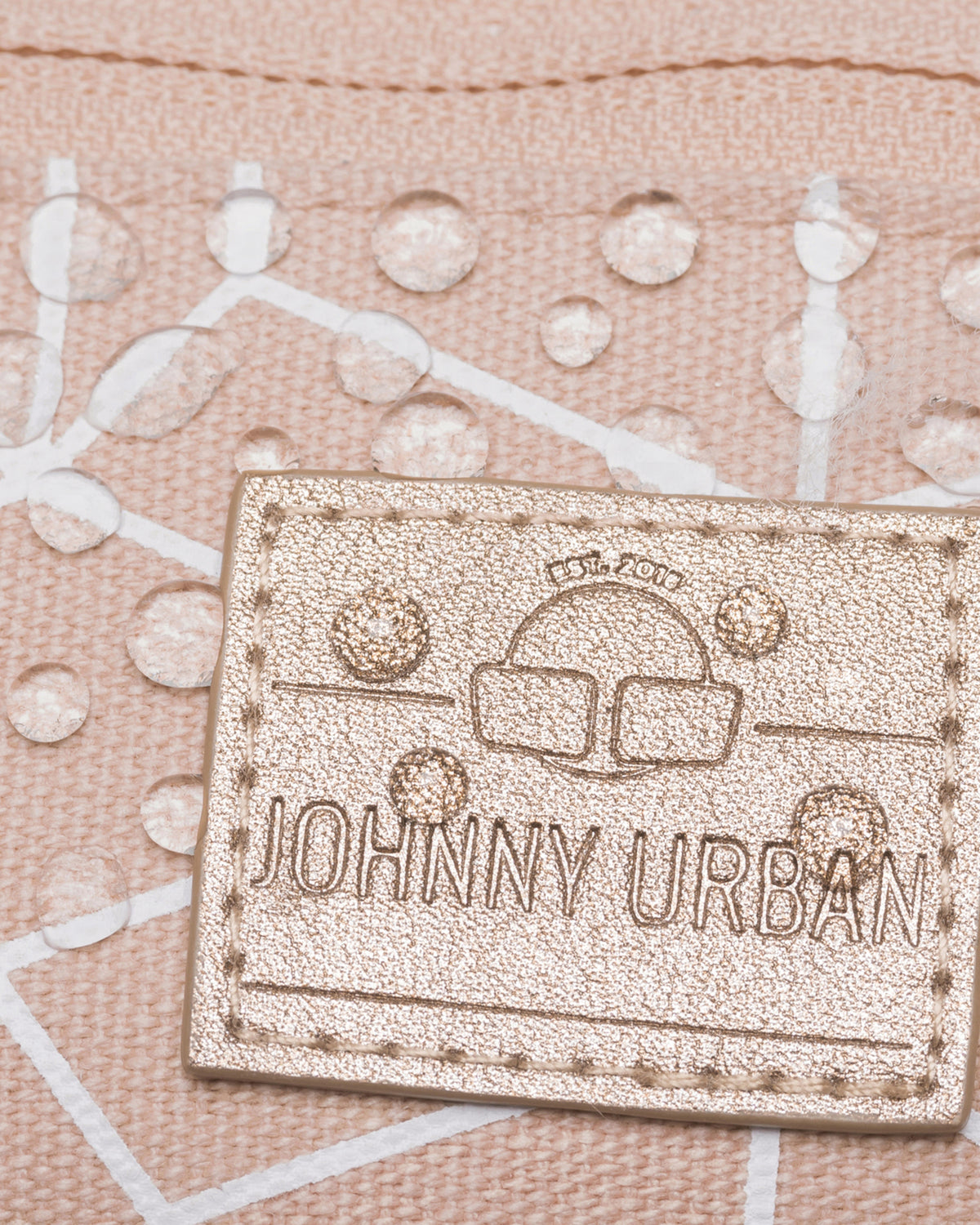 Nahe Ansicht einer rosafarbenen Johnny Urban Bauchtasche mit goldfarbenem Logo, das Wasserdropes abweist