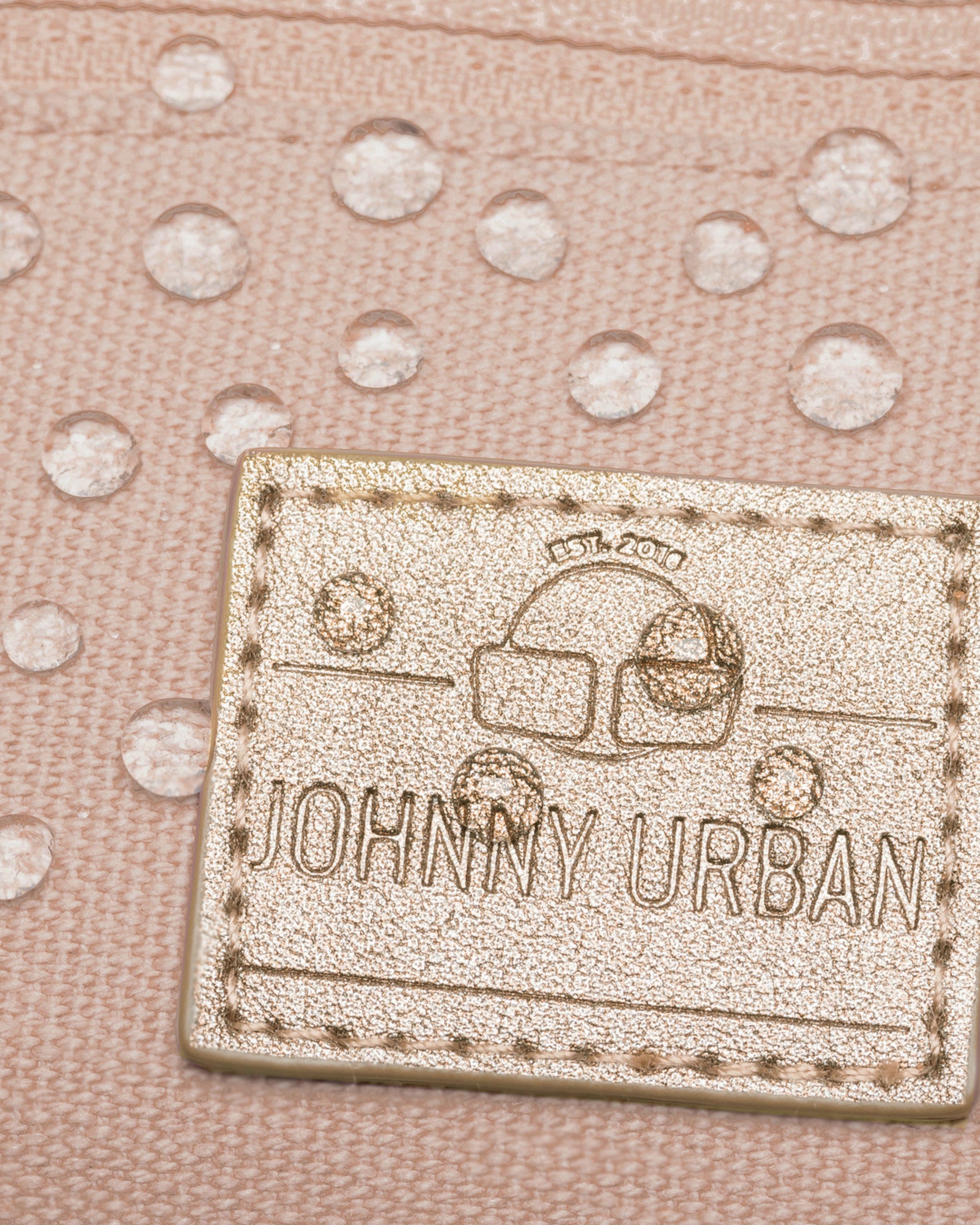Nahaufnahme des wasserabweisenden Canvas-Gewebes und des aufgenähten JOHNNY URBAN Lederlabels der rosa Bauchtasche 'Toni'