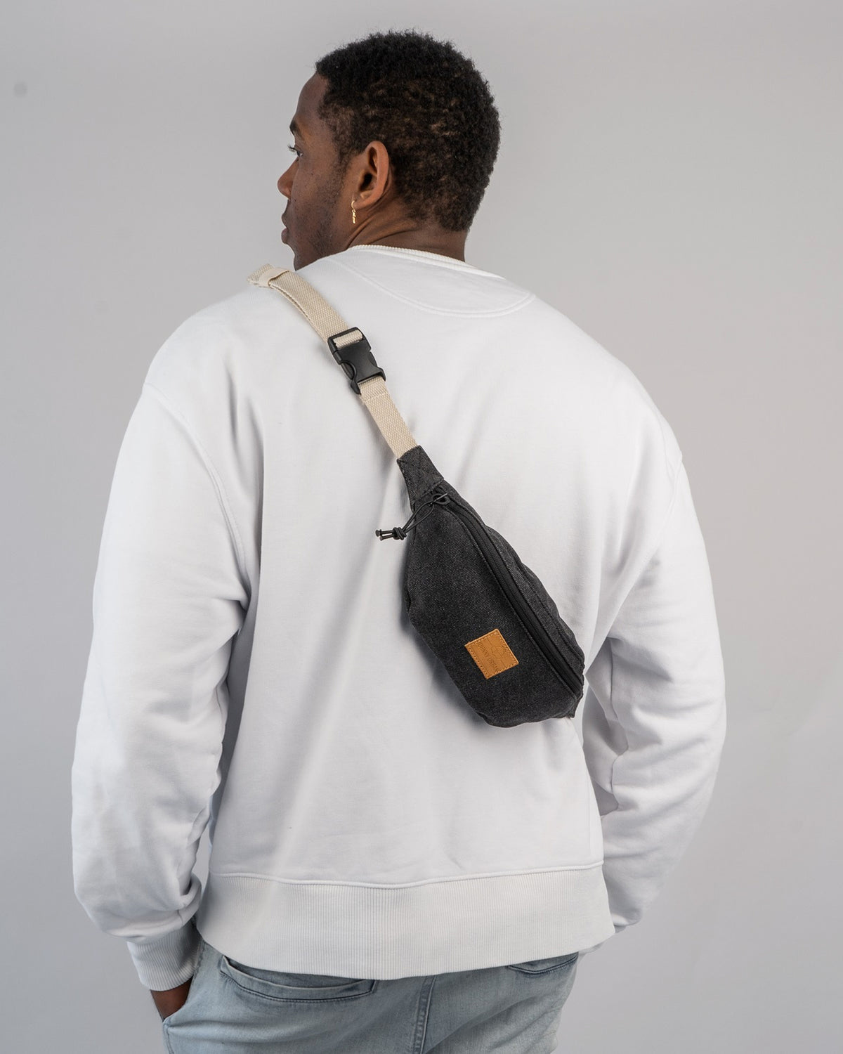 Mann trägt Bauchtasche 'Toni' von Johnny Urban in Anthrazit über der Schulter, weiße Sweatshirt