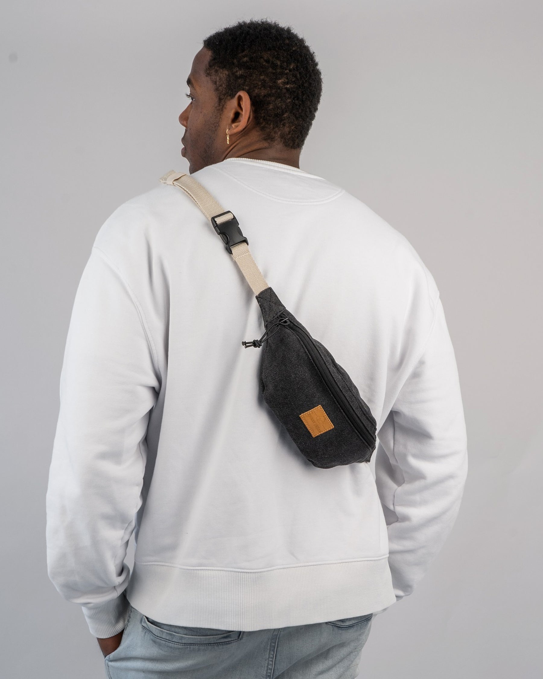 Mann trägt Bauchtasche 'Toni' von Johnny Urban in Anthrazit über der Schulter, weiße Sweatshirt