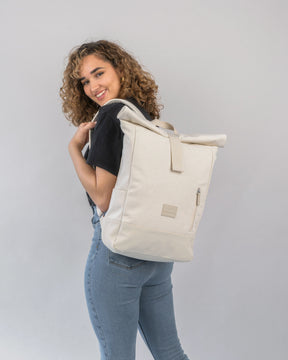 Frau trägt hellbeigen Rolltop Rucksack 'Adam Medium' aus Canvas mit Reißverschlussfach hinten
