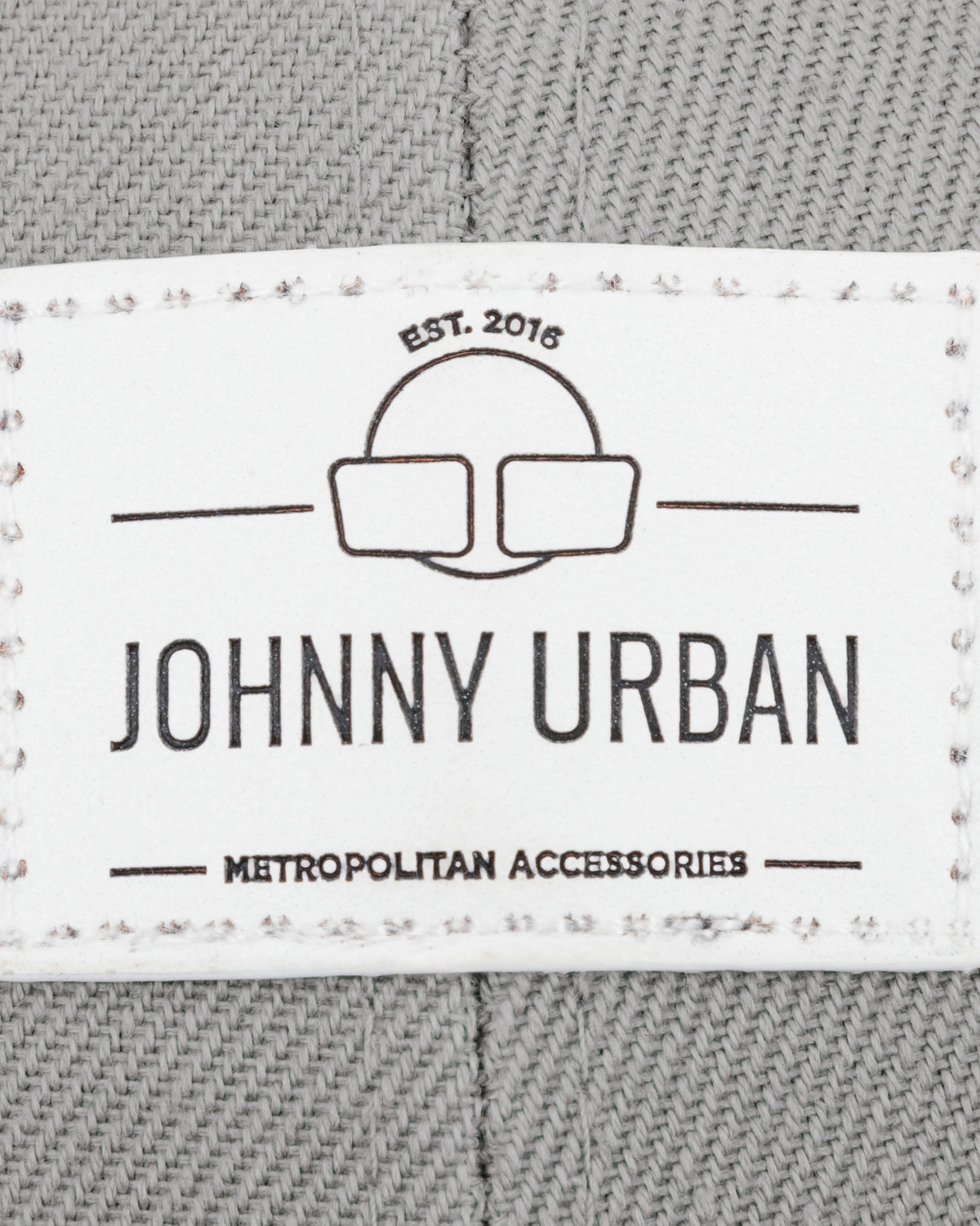 Label mit Logo und Text 'Johnny Urban Metropolitan Accessories EST. 2016' auf grauem Canvasstoff der Cap 'Dean' curved