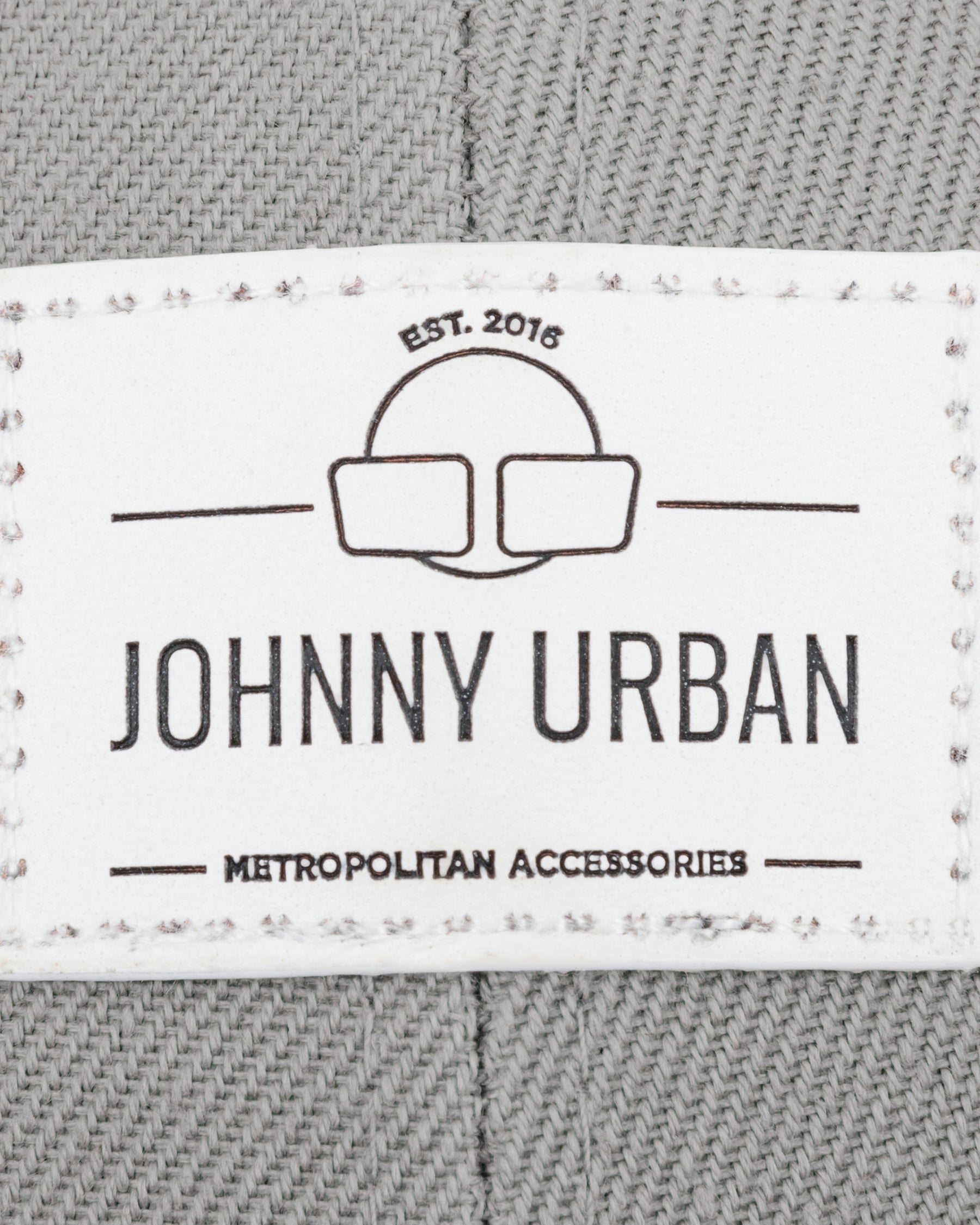 Label mit Logo und Text 'Johnny Urban Metropolitan Accessories EST. 2016' auf grauem Canvasstoff der Cap 'Dean' curved