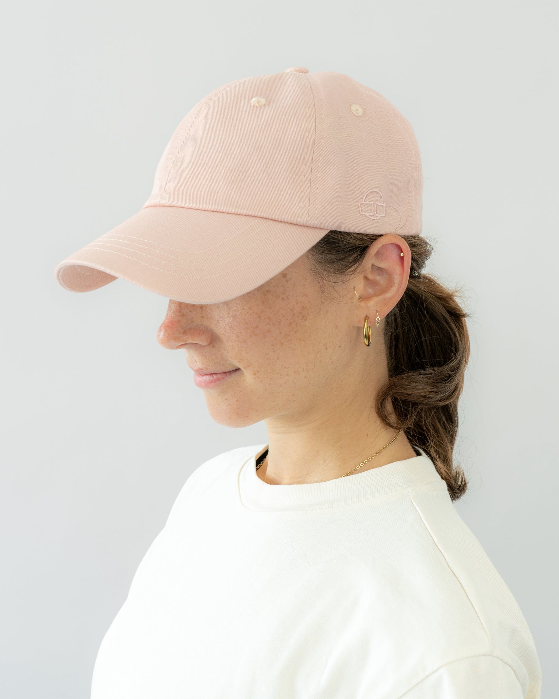 Frau mit rosa Cap 'Jen' von Johnny Urban, seitlich gesehen, getragen zu weißem Oberteil