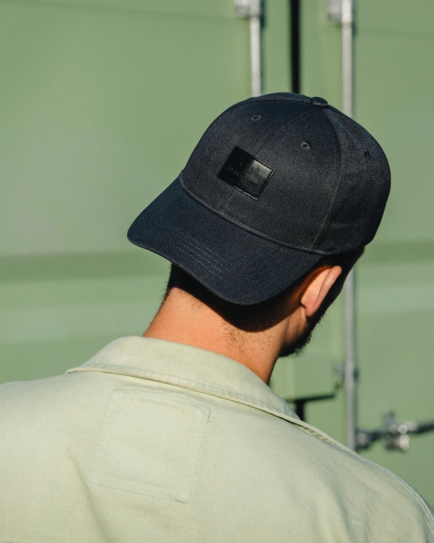 Schwarze, gewölbte Herren-Cap 'Dean' mit Lederpatch auf dem Kopf eines Mannes von hinten